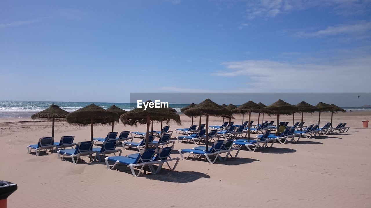 Panoramic view of lounge chairs on beach against sky ocean 