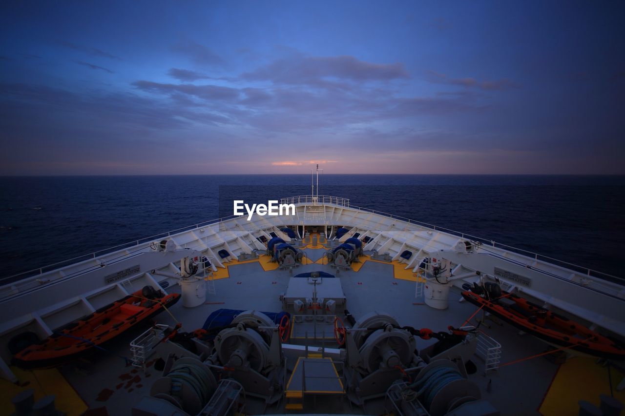 Cropped image of cruise ship in sea against sky at dusk