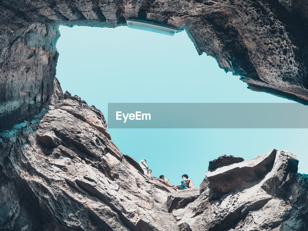 LOW ANGLE VIEW OF PEOPLE ON ROCK FORMATION