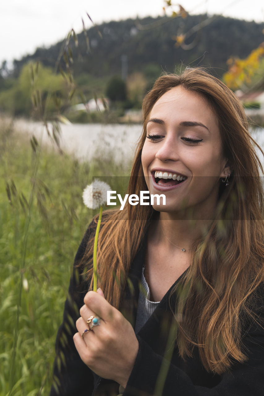 Cheerful woman with blowball enjoying in nature