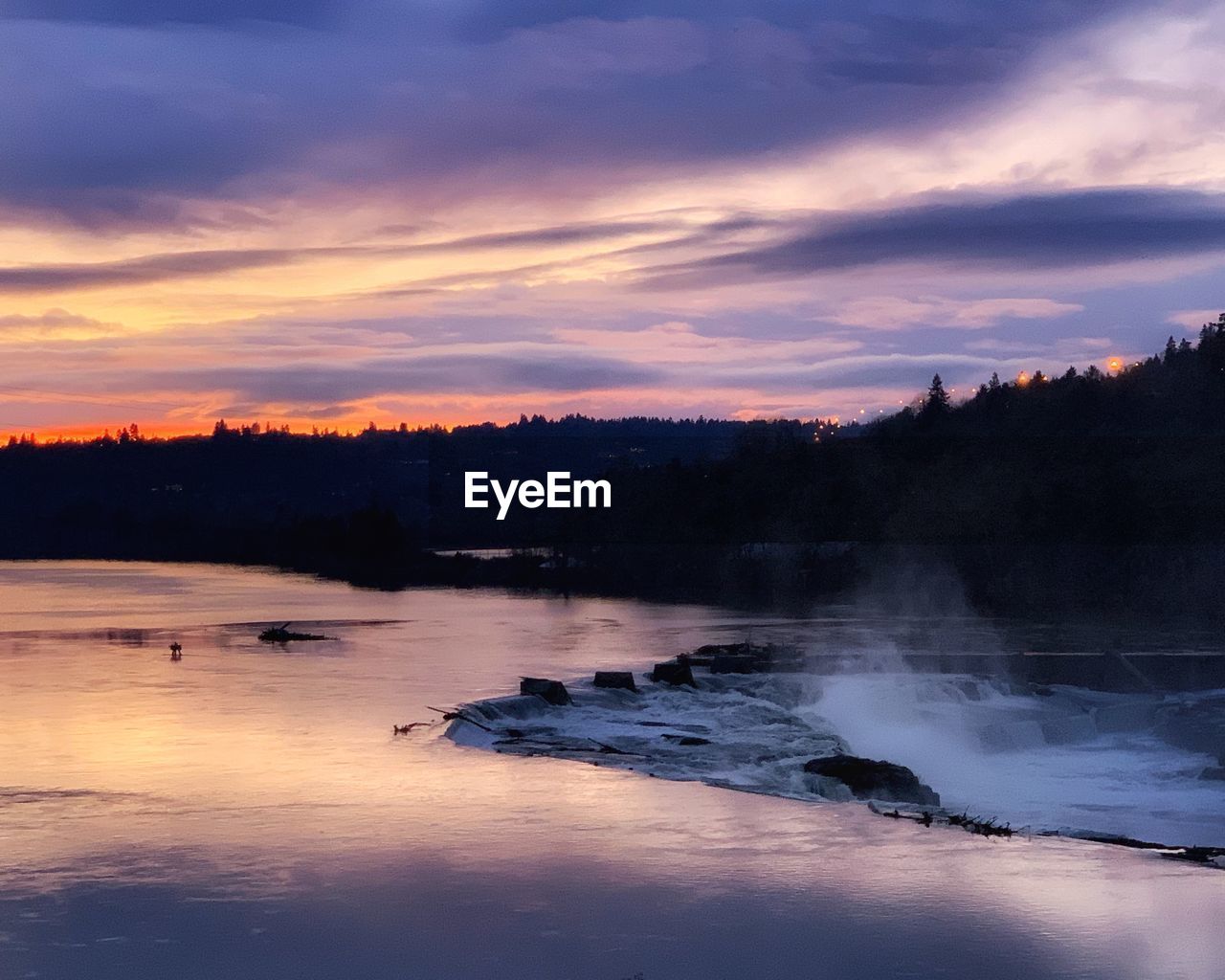 Scenic view of waterfall against sky at sunset