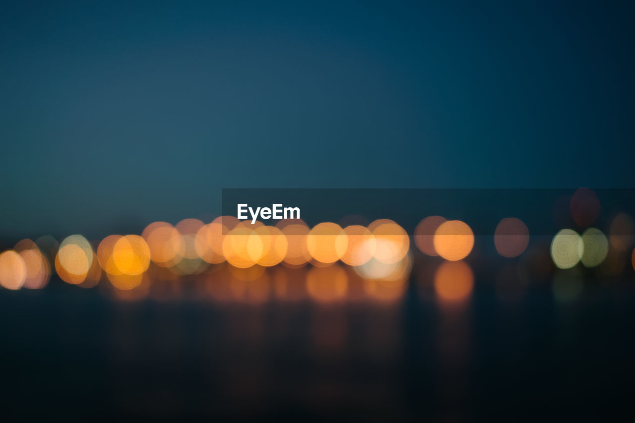 DEFOCUSED IMAGE OF ILLUMINATED LIGHTS AT NIGHT