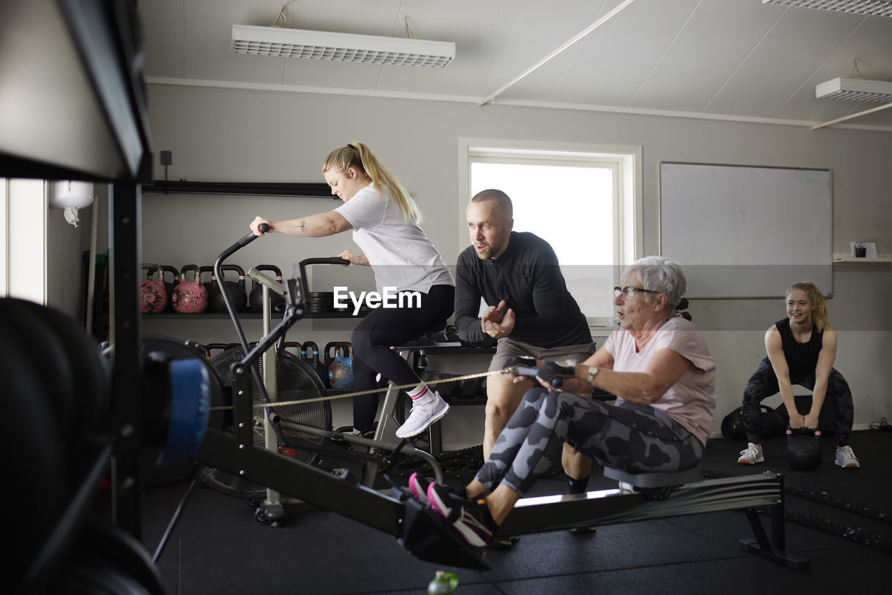 Coach assisting to senior woman exercising in gym