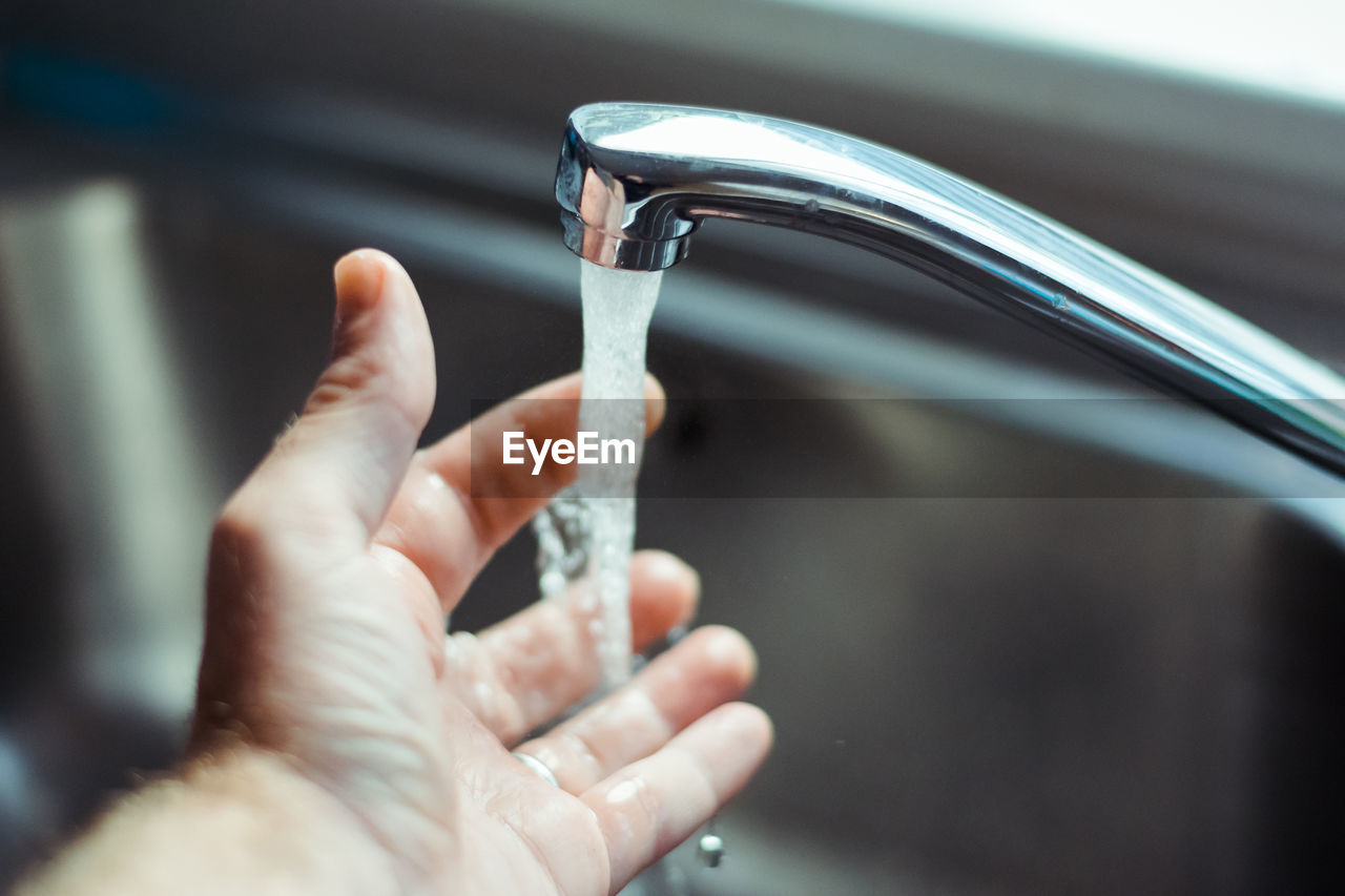 Cropped image of person washing hand in faucet
