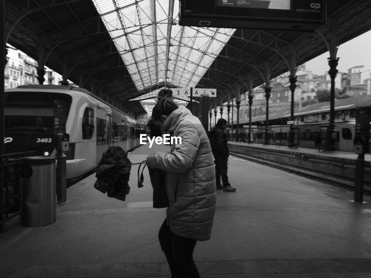 REAR VIEW OF PEOPLE ON RAILROAD STATION PLATFORM