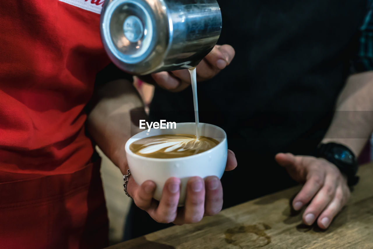 MIDSECTION OF MAN HOLDING COFFEE CUPS