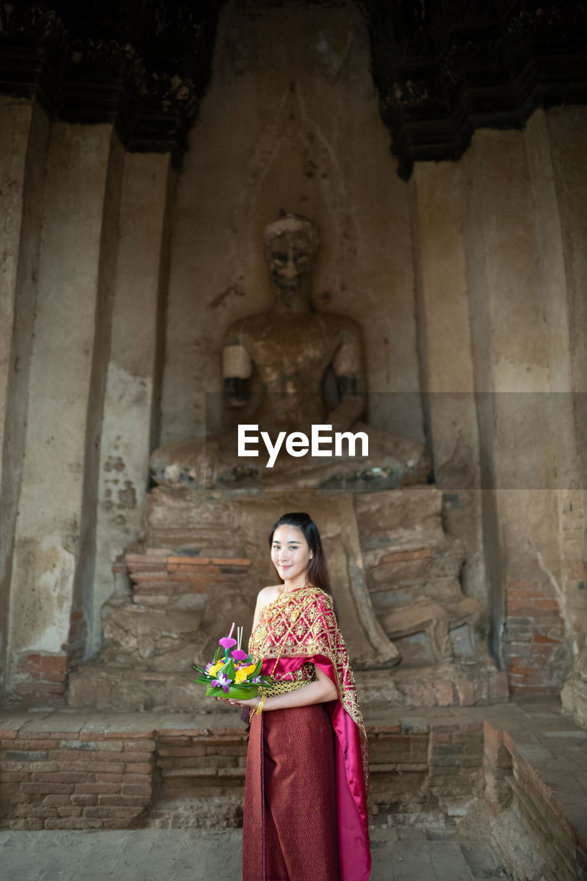 Woman standing against buddha statue at temple