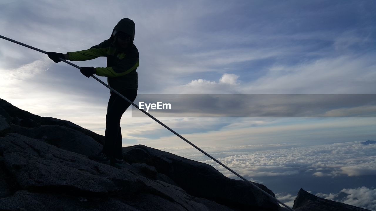 LOW ANGLE VIEW OF MAN AGAINST MOUNTAIN