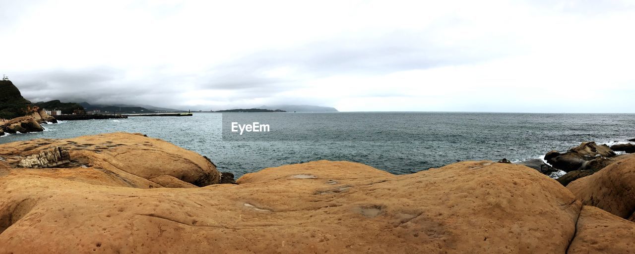 SCENIC VIEW OF ROCKS ON BEACH AGAINST SKY