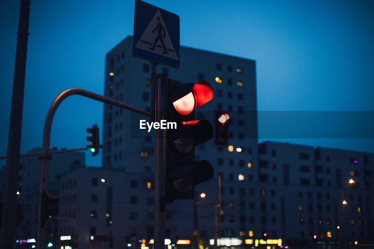 Low angle view of stoplight against building at dusk