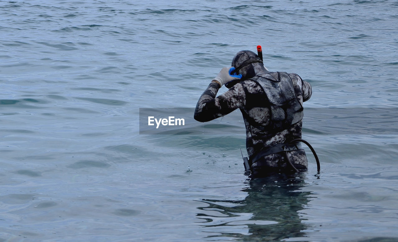 Rear view of diver standing in sea