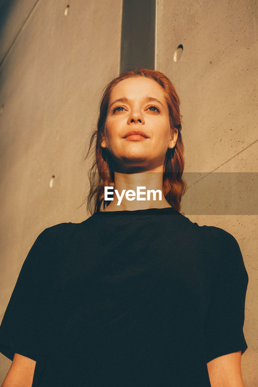 Low angle view of woman standing against wall
