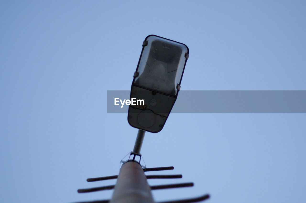 Low angle view of street light and antenna against clear blue sky