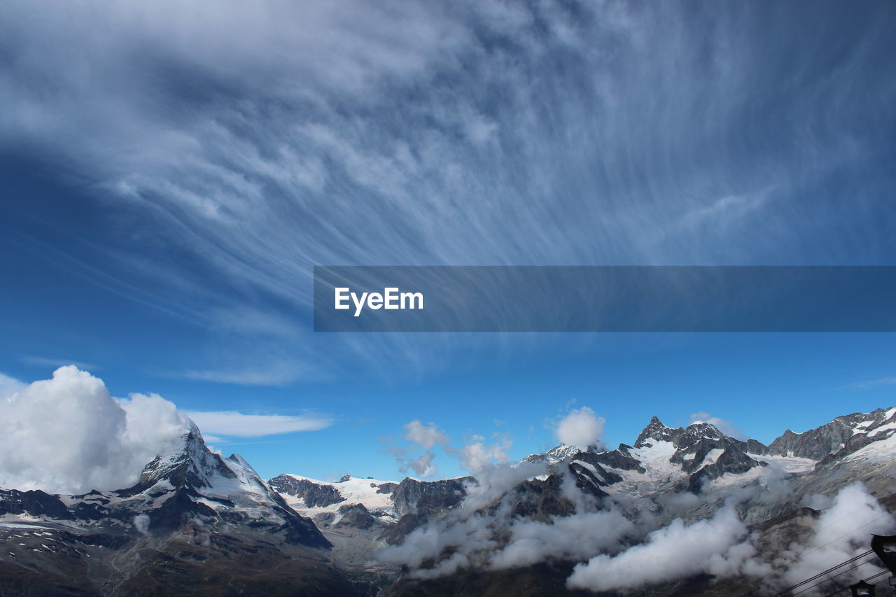 Scenic view of snowcapped mountains against blue sky