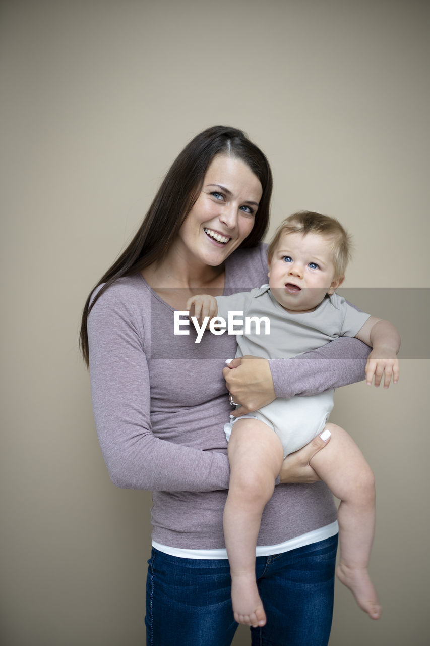 portrait of smiling mother carrying daughter