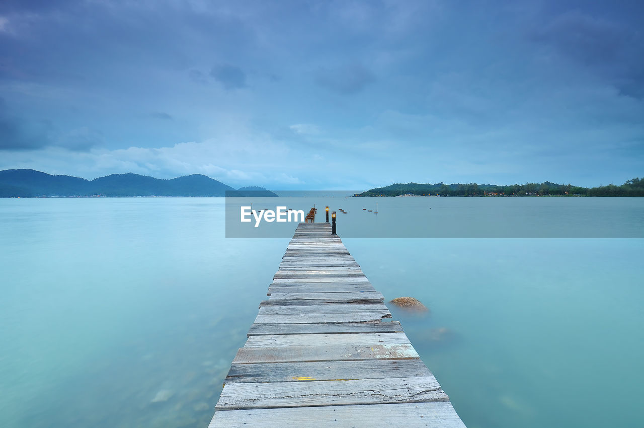 Pier over lake against blue sky