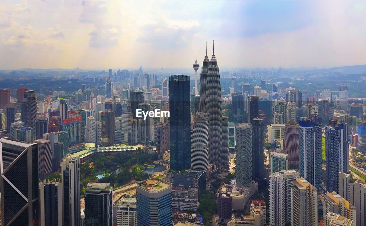 Aerial view of city buildings against cloudy sky