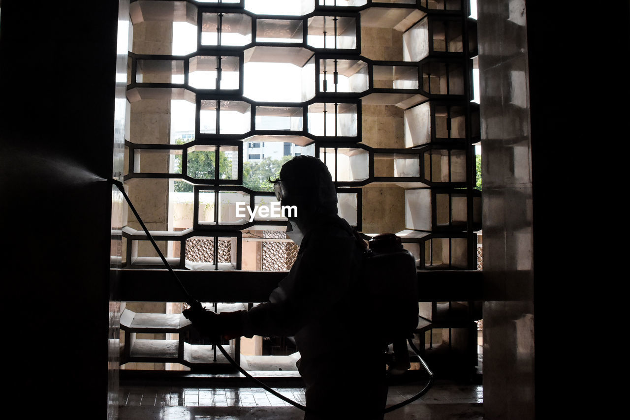 SIDE VIEW OF SILHOUETTE MAN STANDING IN WINDOW