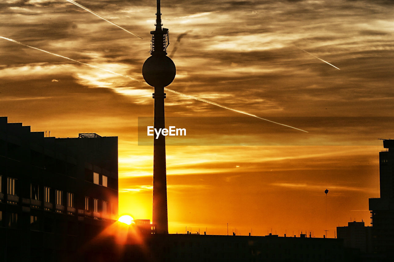 Silhouette fernsehturm in city against sunset sky