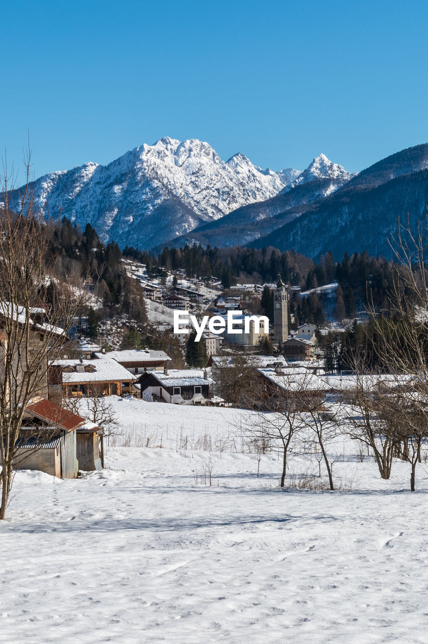 SNOW COVERED BUILDINGS AGAINST MOUNTAIN