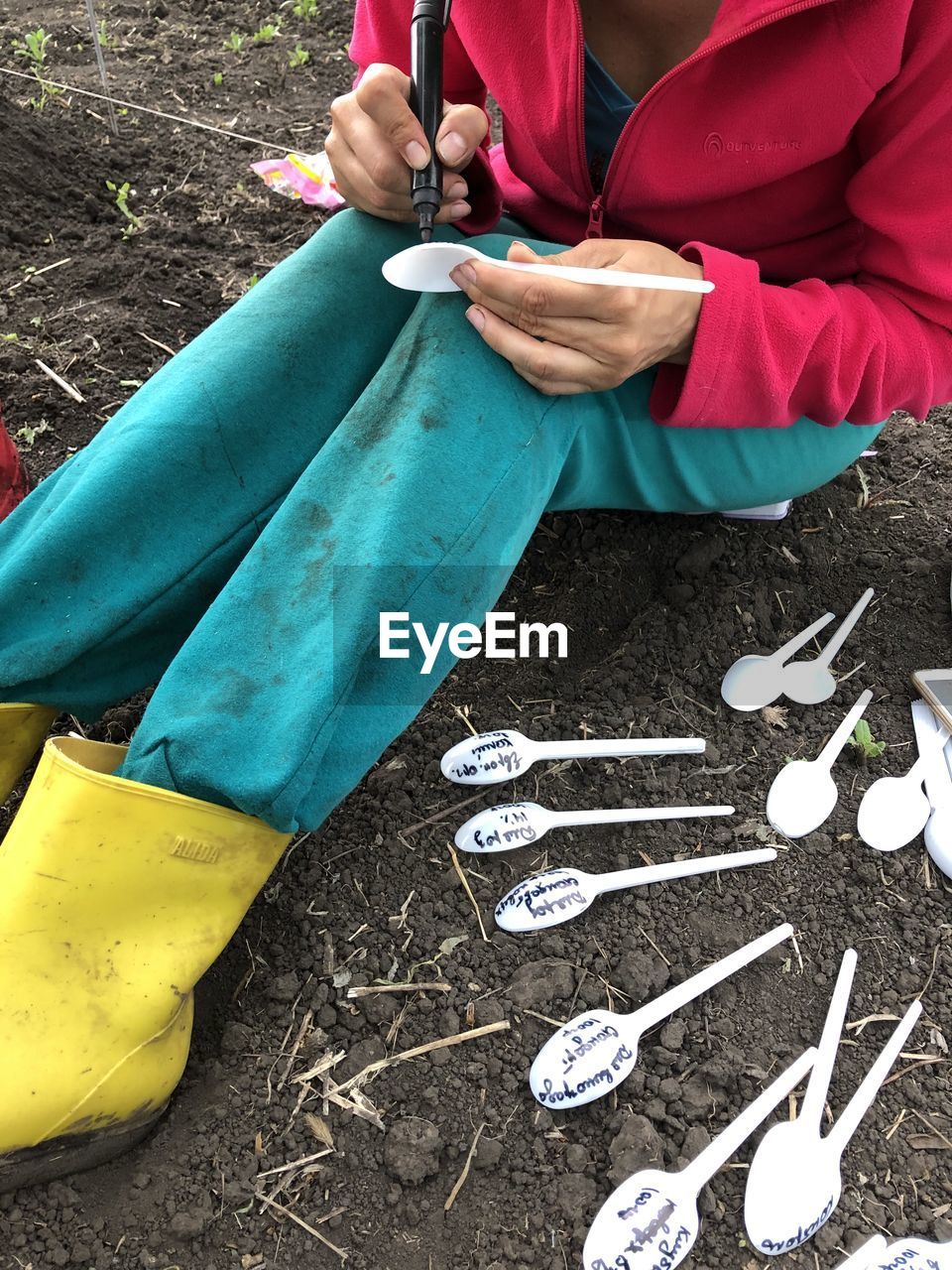 Low section of woman writing on spoon at field