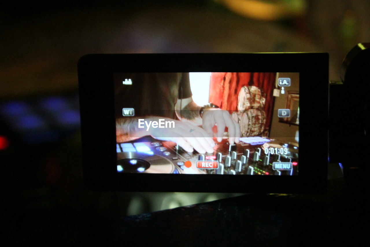 Close-up of video camera against dj using sound mixer at nightclub