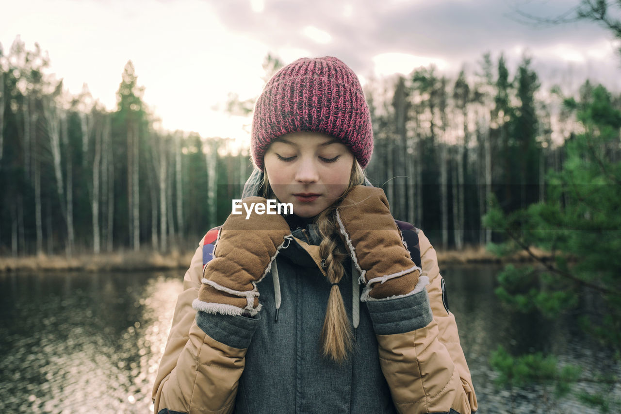 Portrait of young woman in warm clothes by the river