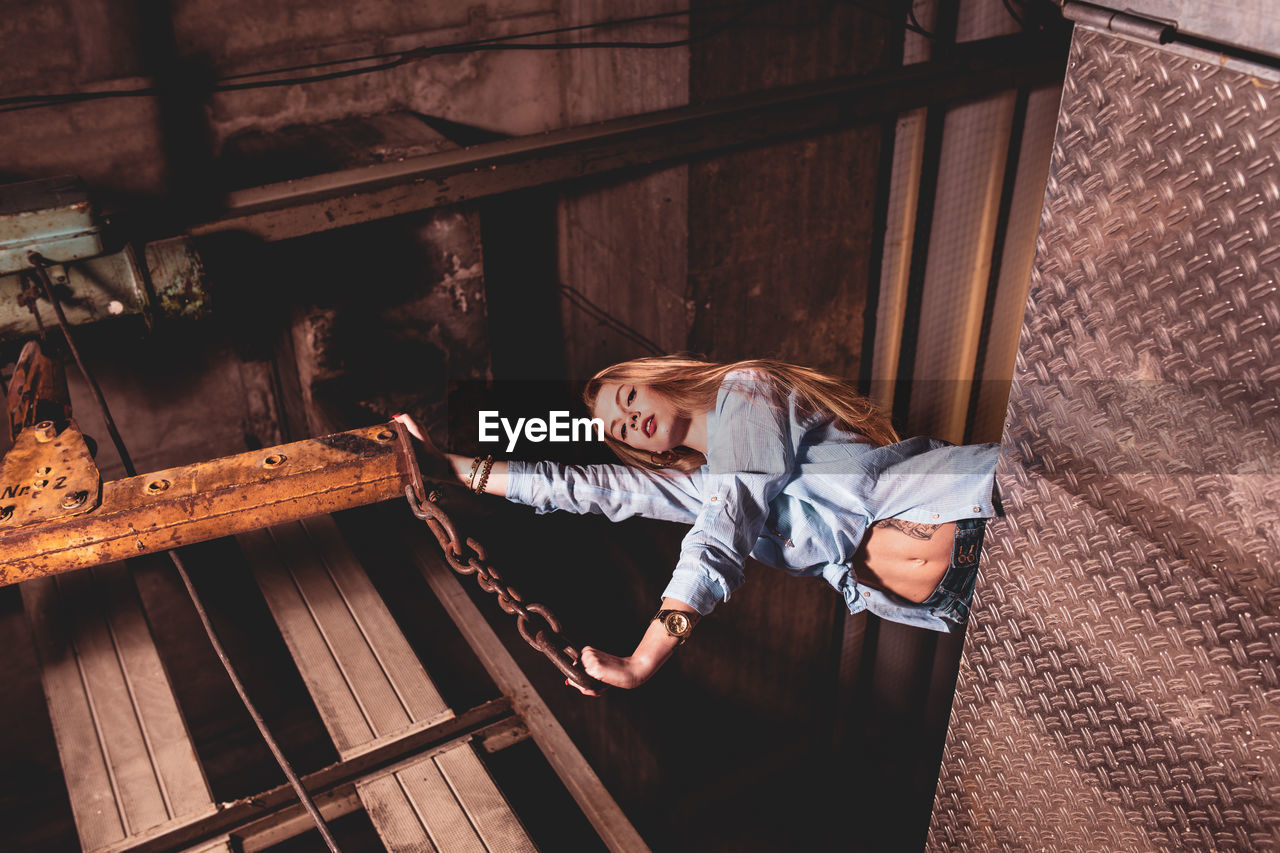 Low angle view of female model posing against metal