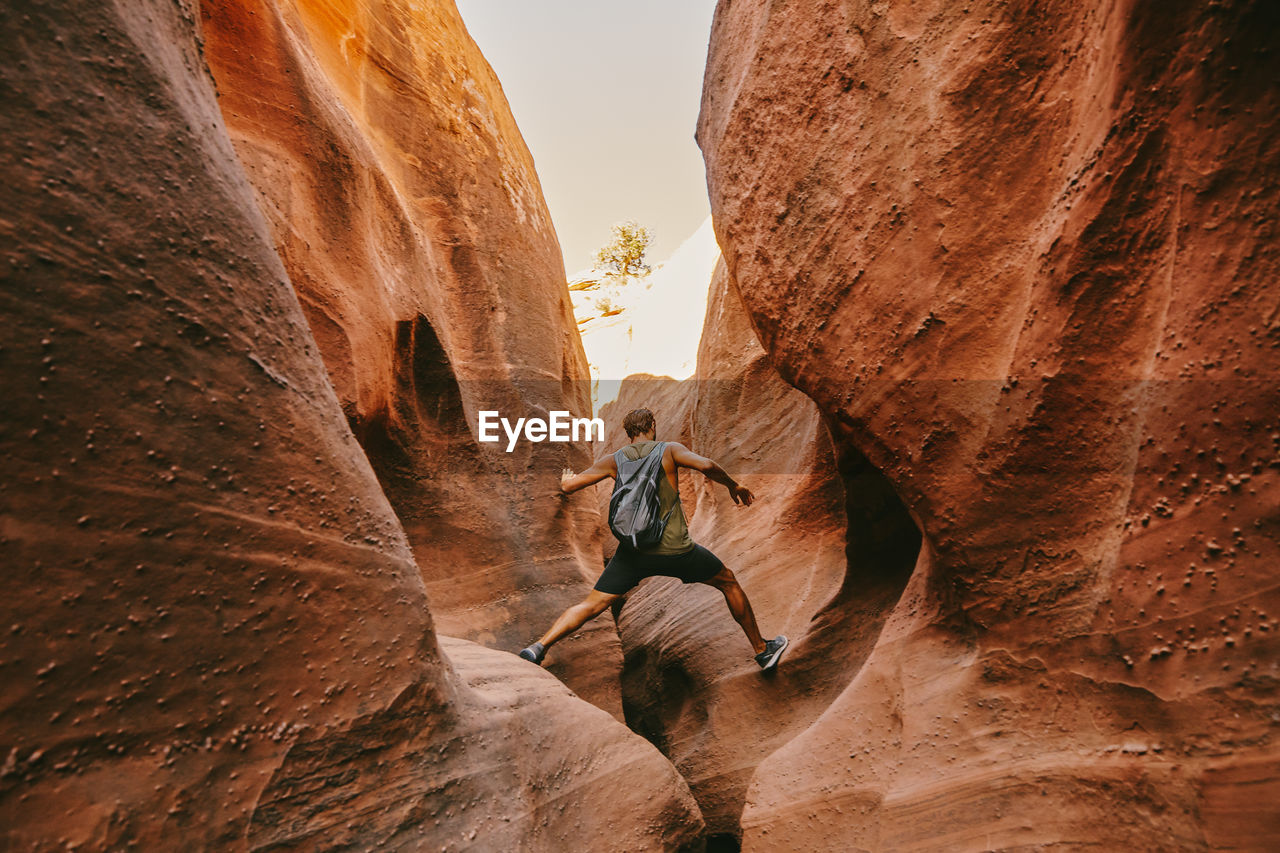 Young man exploring narrow slot canyons in escalante, during summer