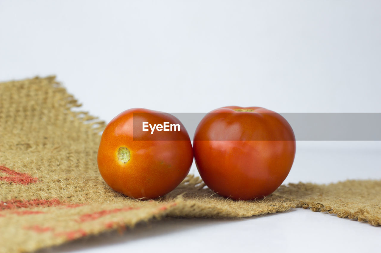Close-up of tomatoes and jute on white background