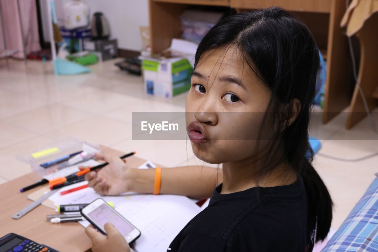 Close-up portrait of girl puckering while studying at home