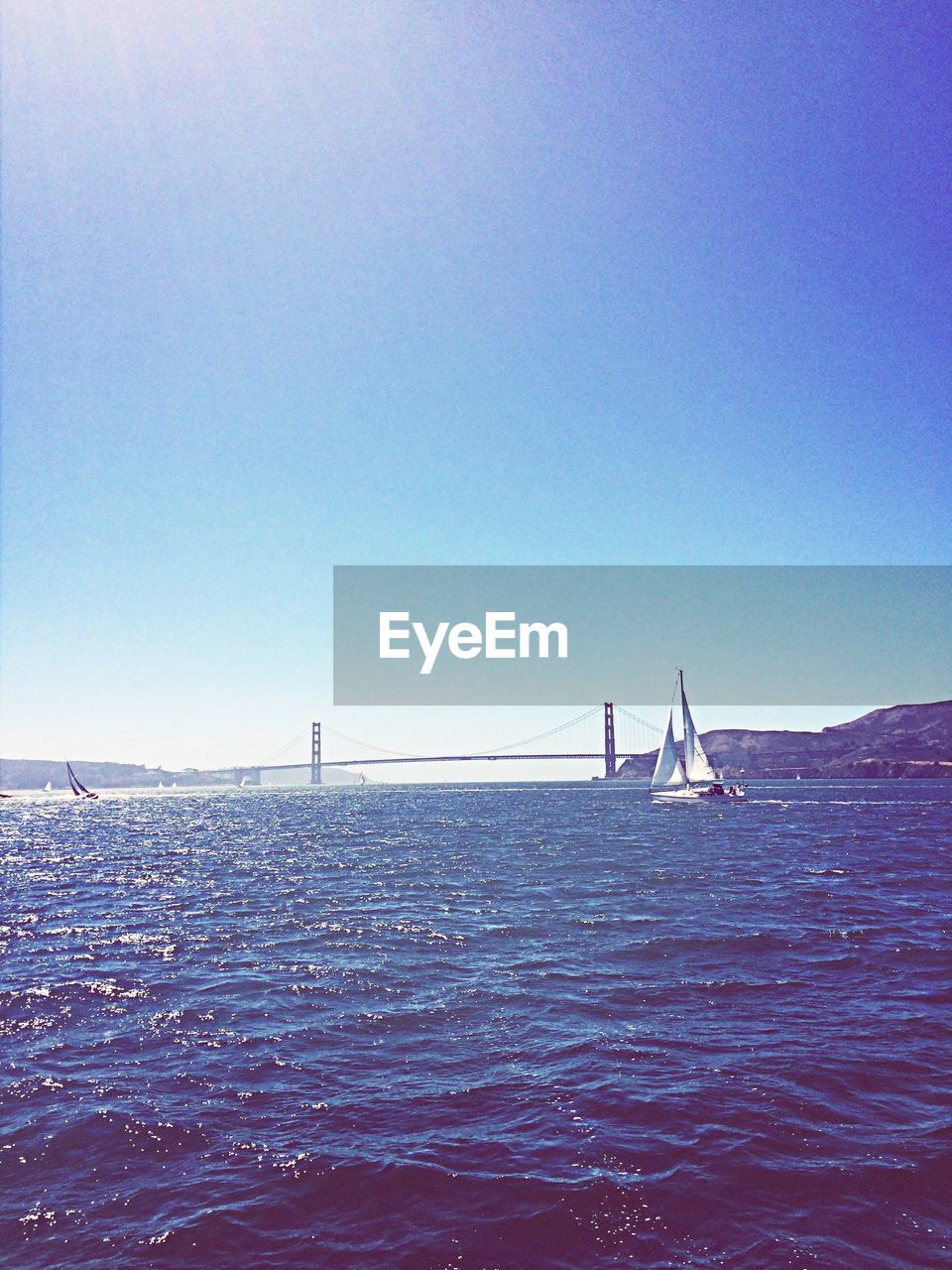 Sailboats sailing in sea against clear blue sky