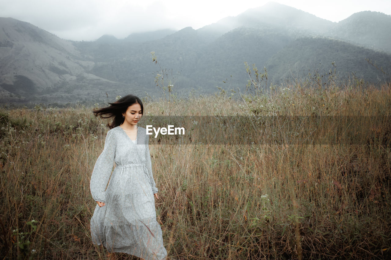 Woman standing on field against mountains