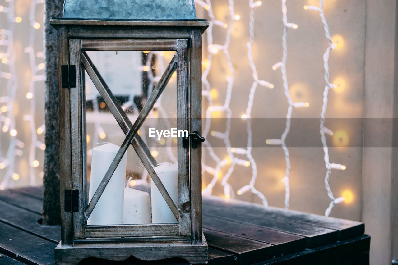 Close-up of illuminated lamp against window at sunset