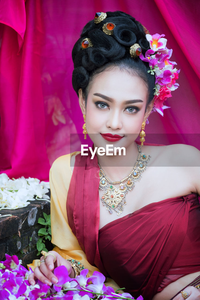 Portrait of beautiful young woman with pink orchids wearing traditional clothing