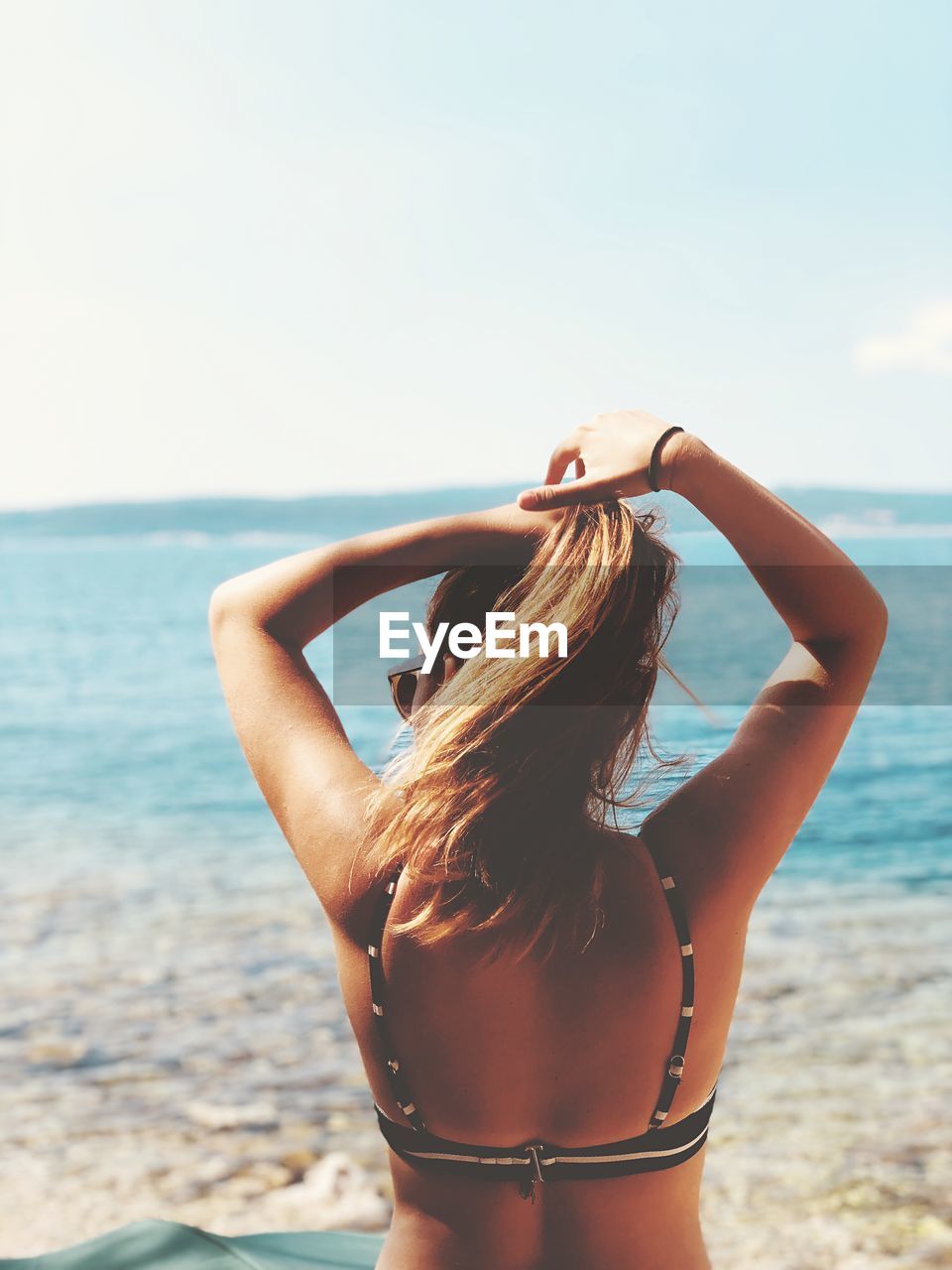 REAR VIEW OF WOMAN STANDING ON BEACH