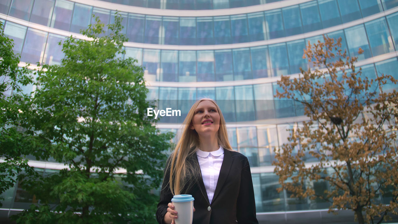 portrait of smiling young woman standing against trees