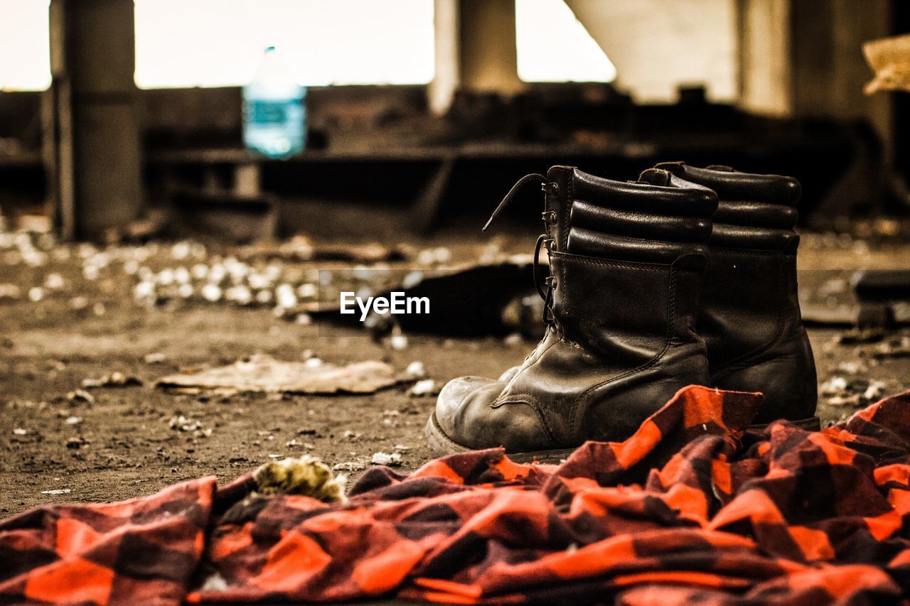 Close-up of old shoes and shirt inside of an abandoned place