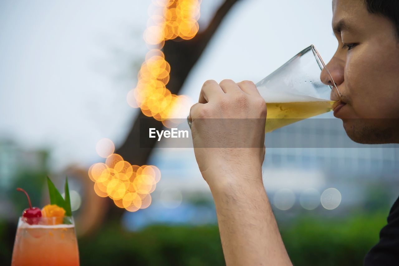 Close-up of man drinking beer in glass