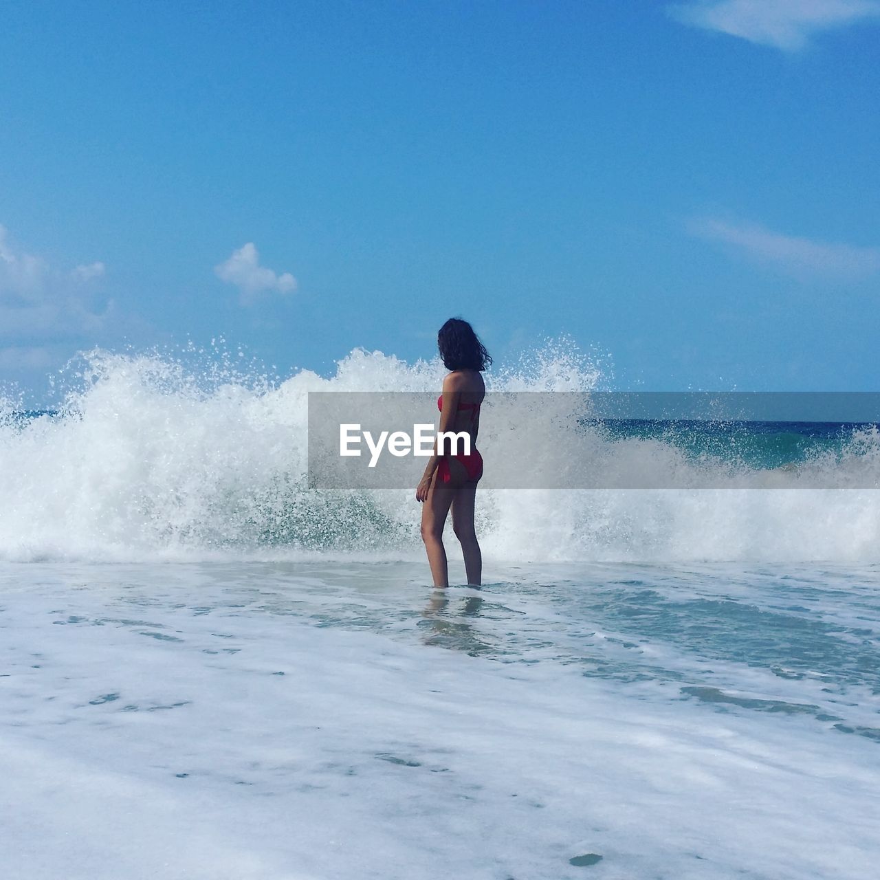 Woman in bikini standing in sea against sky