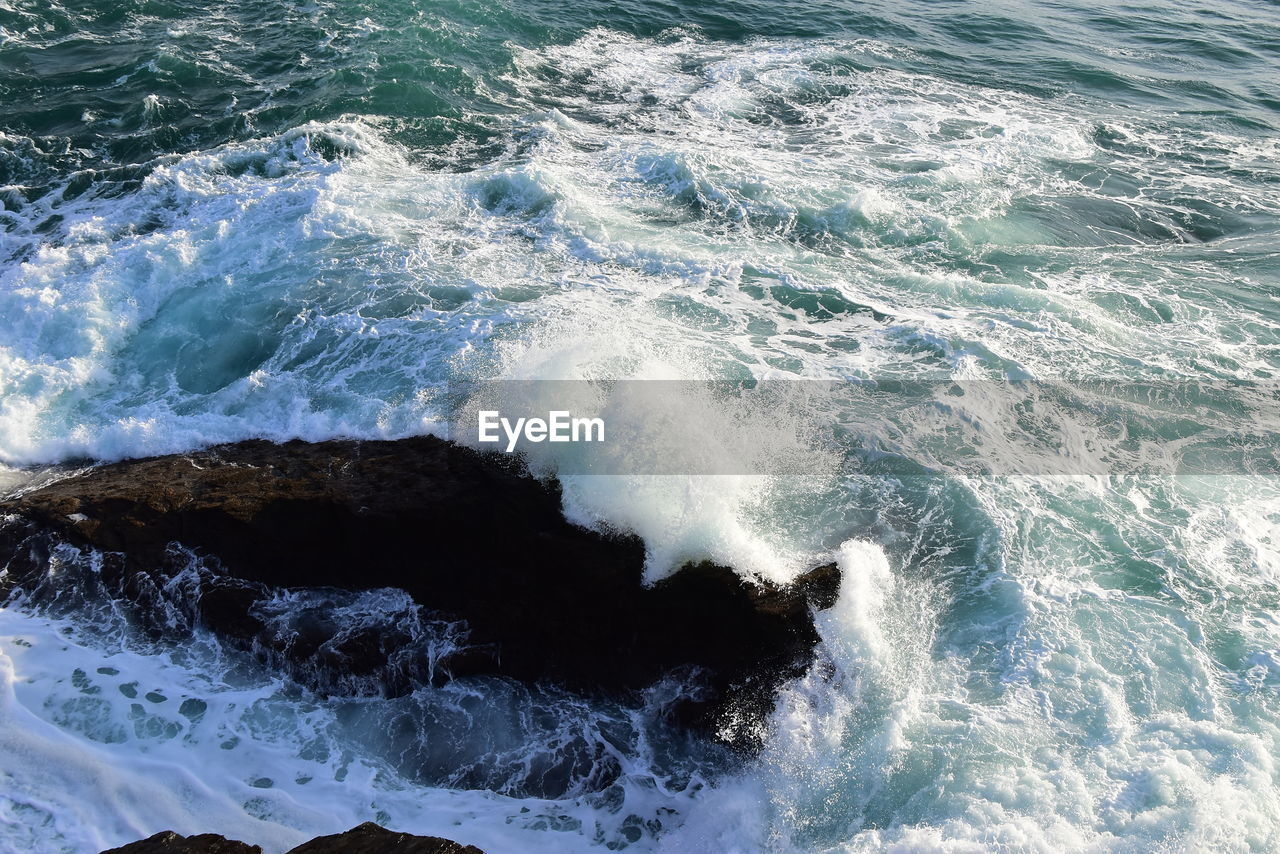 High angle view of waves splashing on rocks