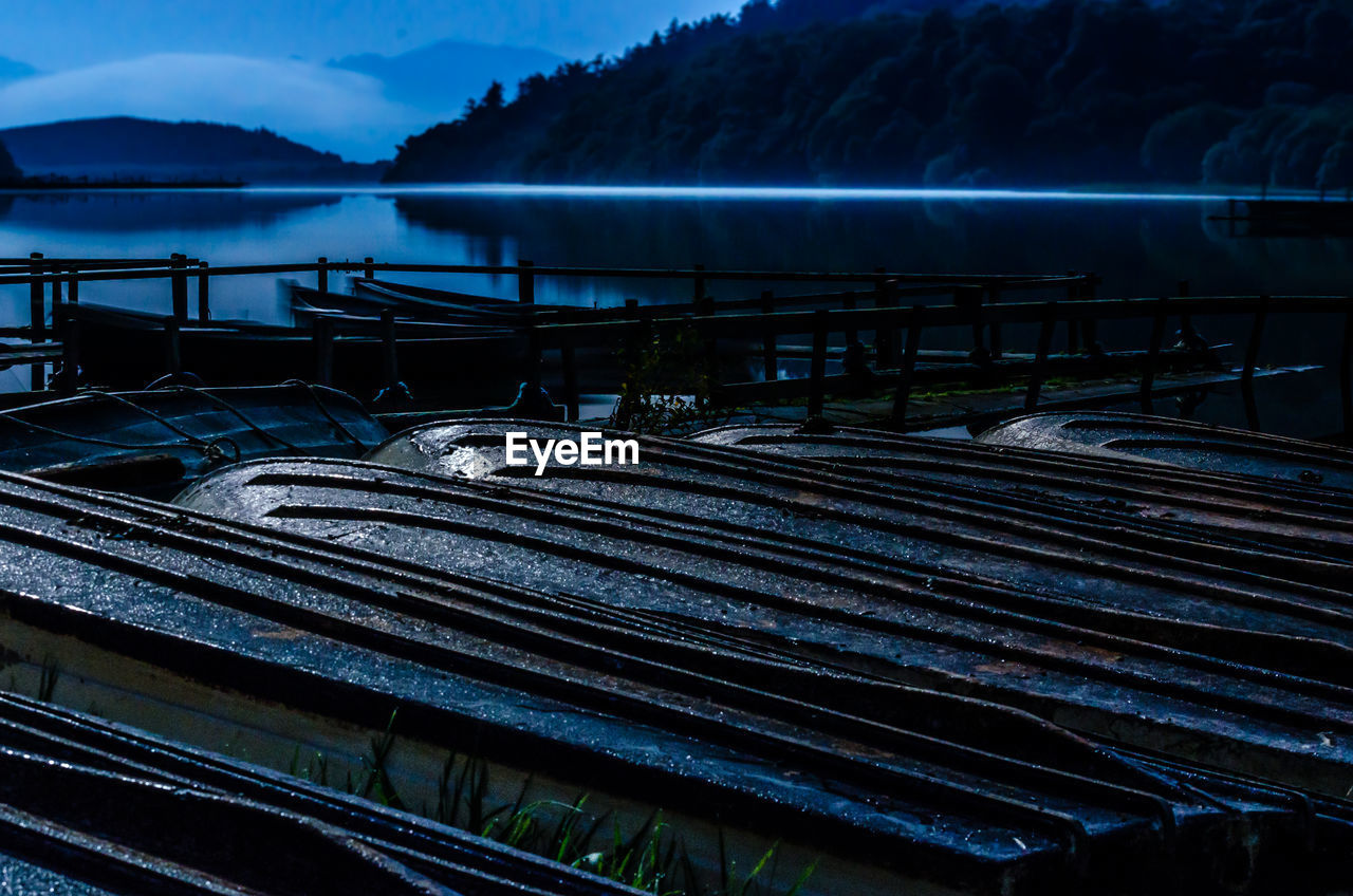 Boats moored on lake during dusk