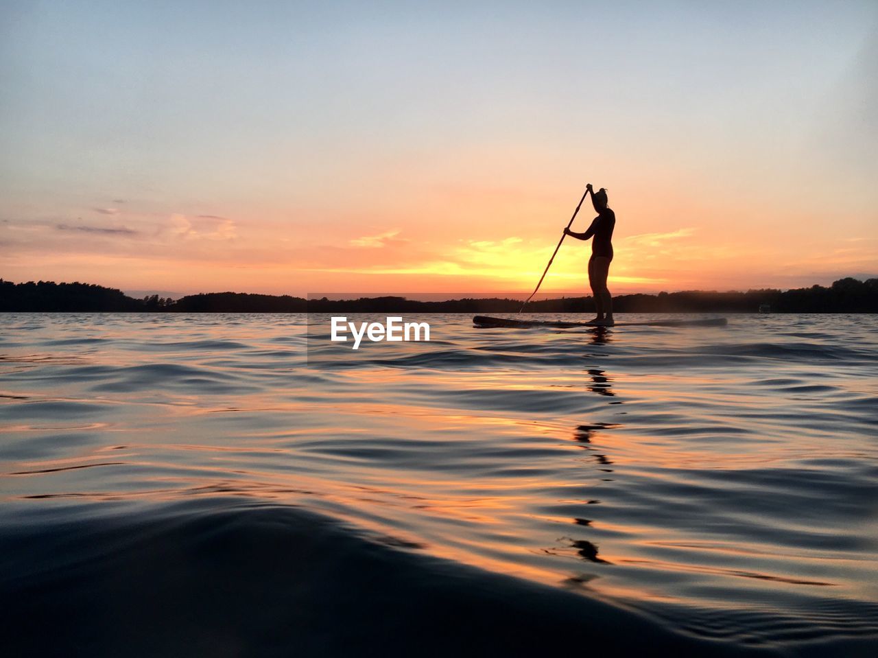 Silhouette woman standing in boat against sky during sunset