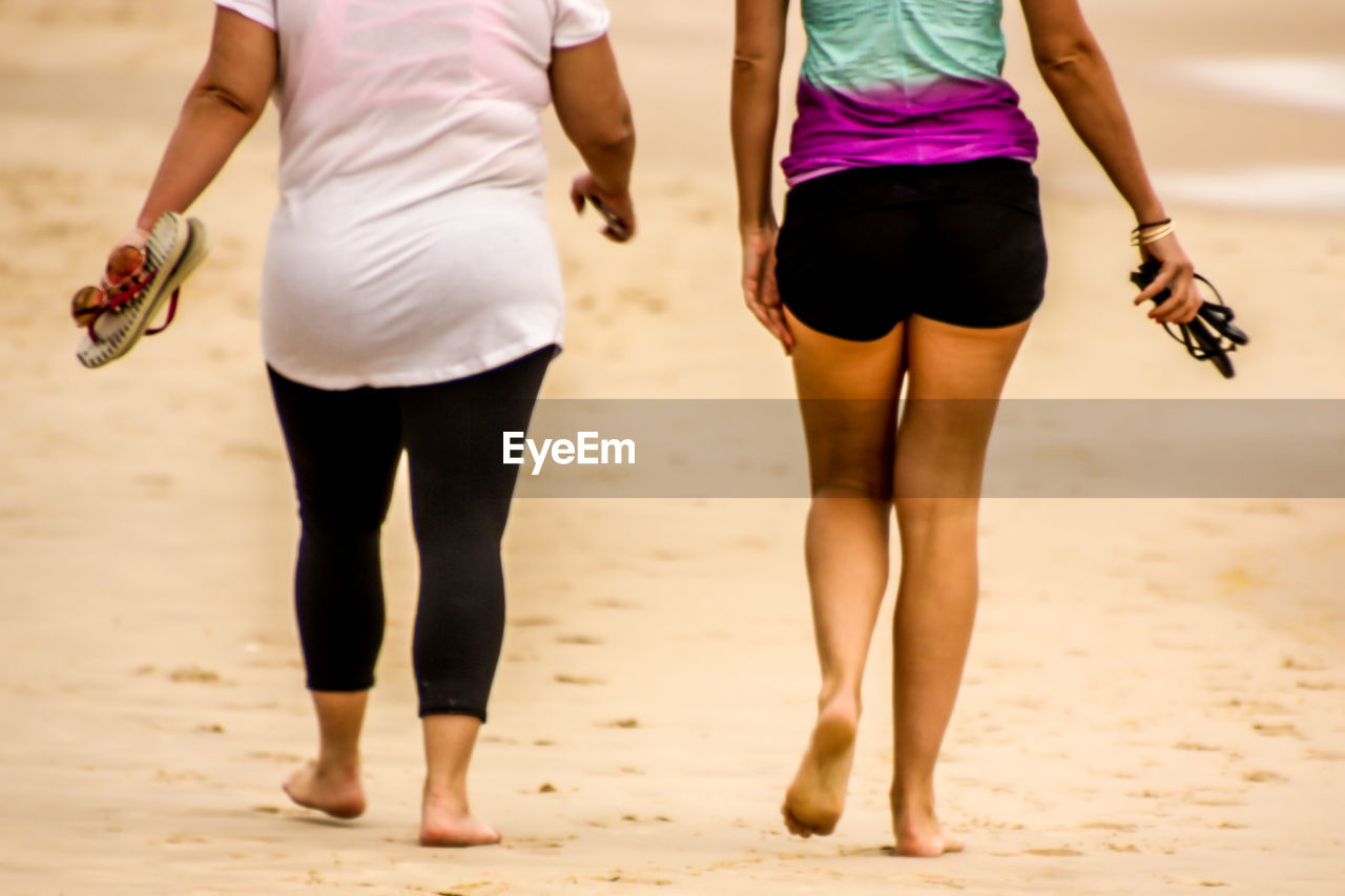 Low section of people walking on beach