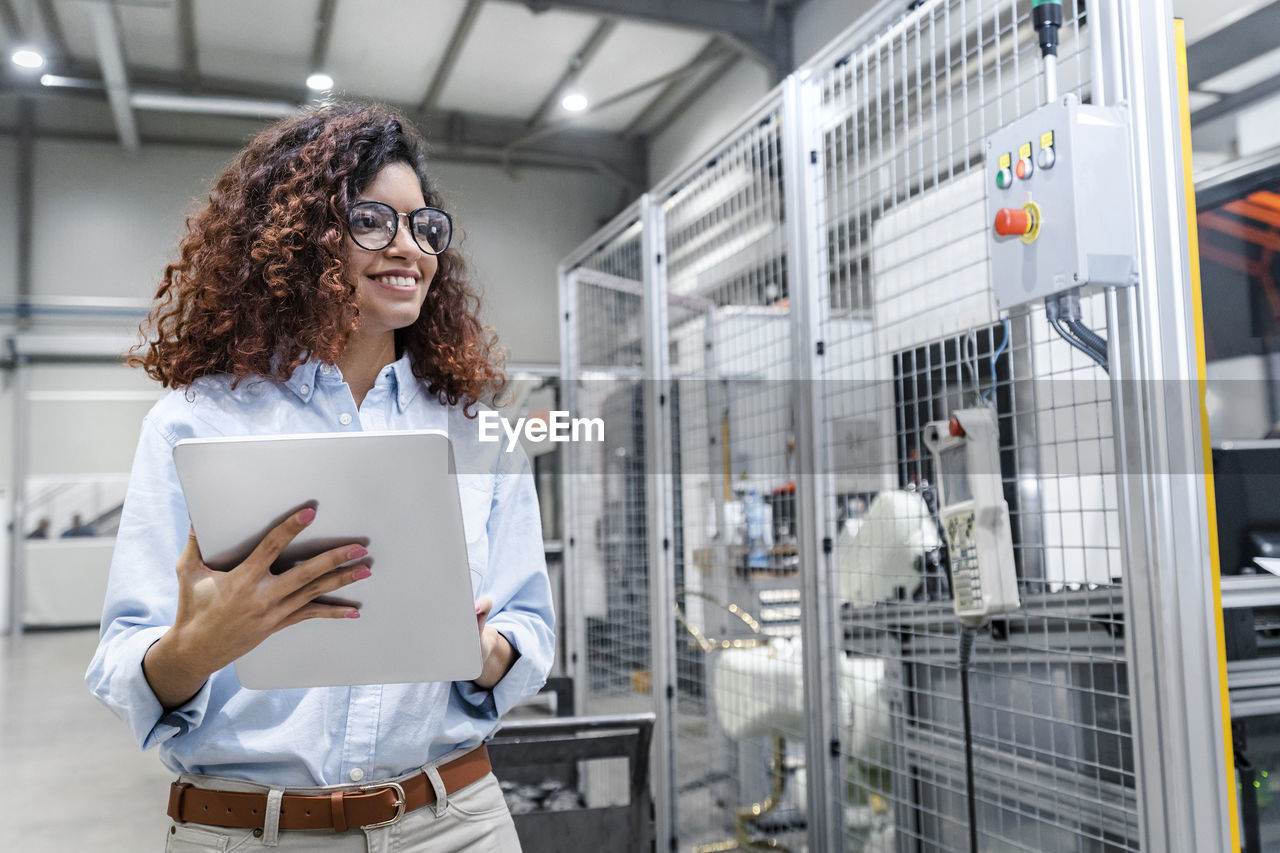 Happy engineer with tablet pc standing in industry