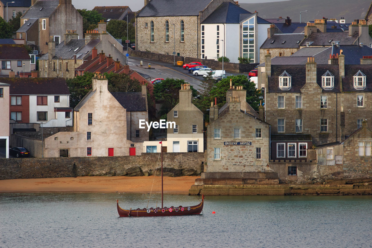 Sailboats in city by river in town