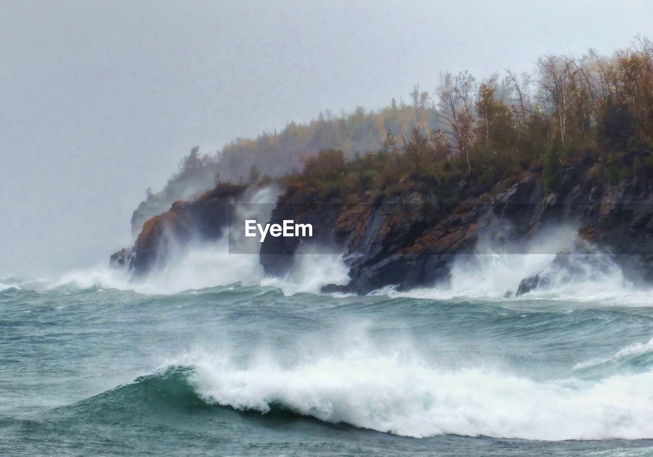 SCENIC VIEW OF WAVES SPLASHING ON SEA AGAINST SKY