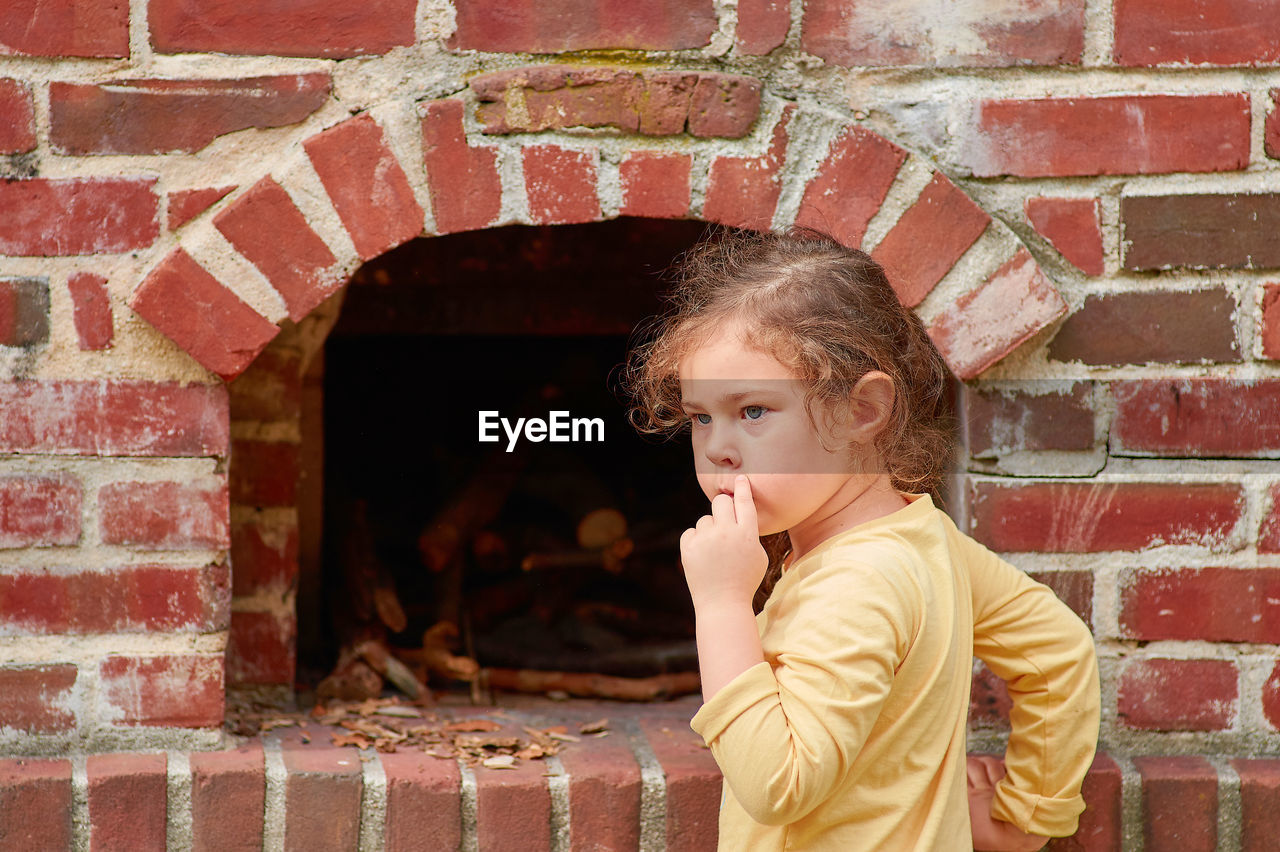 Pretty young girl playing with a brick stove at a farming exhibition