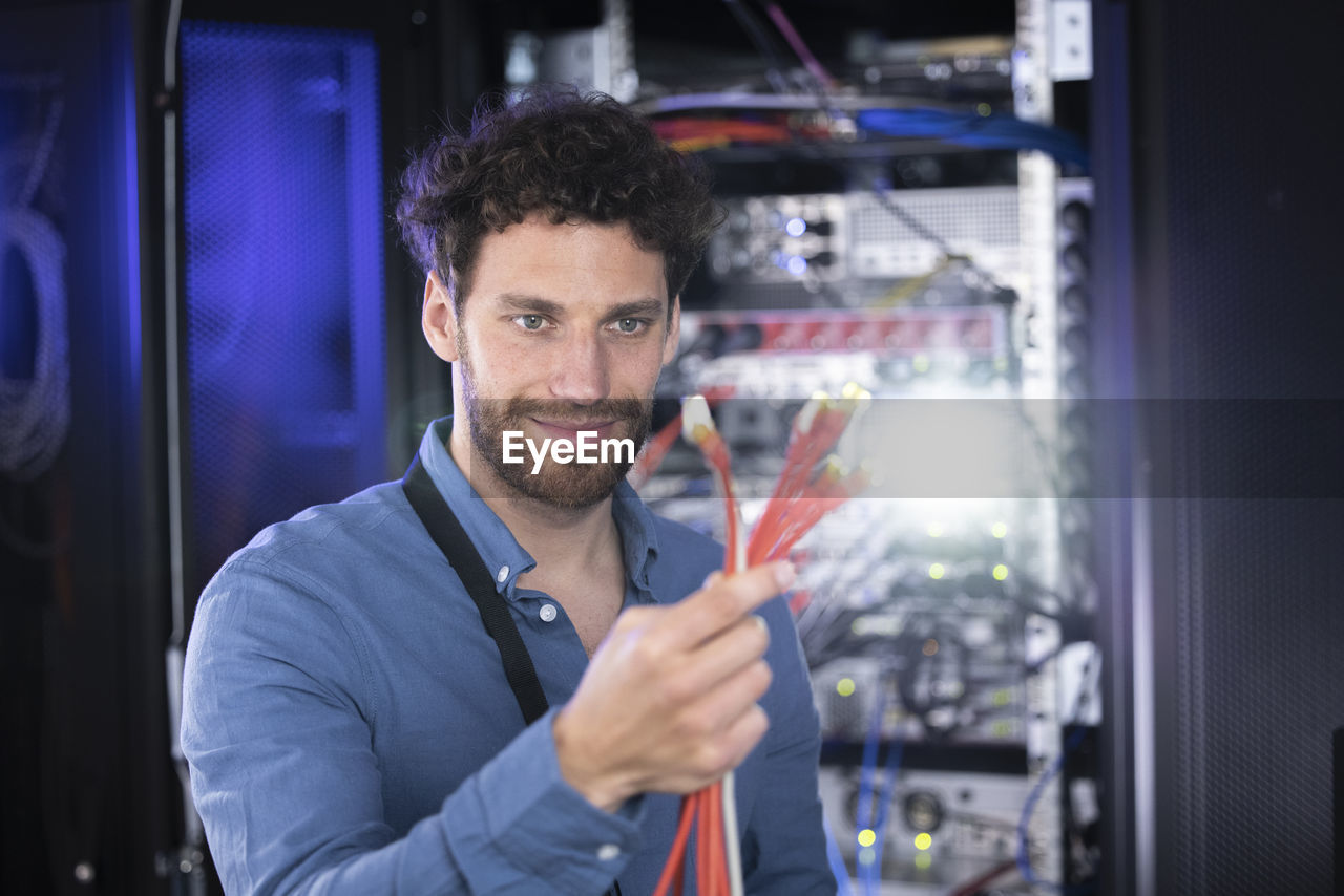 Male it specialist looking at patch cord cables in server room