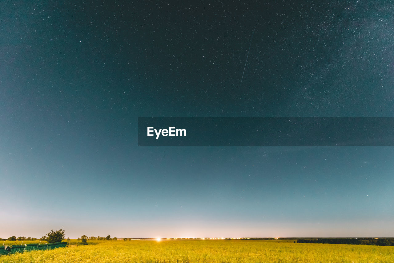 scenic view of field against clear blue sky at night